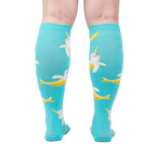 Rear view of model wearing teal Bananarwhal knee-high socks; showing the full sock design.