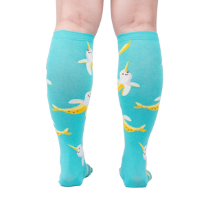 Rear view of model wearing teal Bananarwhal knee-high socks; showing the full sock design.