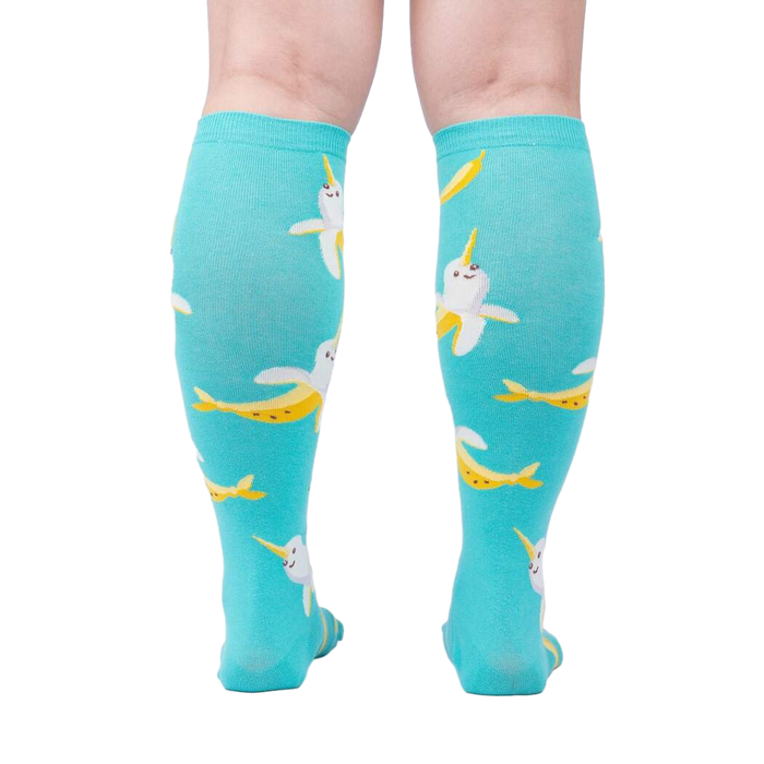 Rear view of model wearing teal Bananarwhal knee-high socks; showing the full sock design.