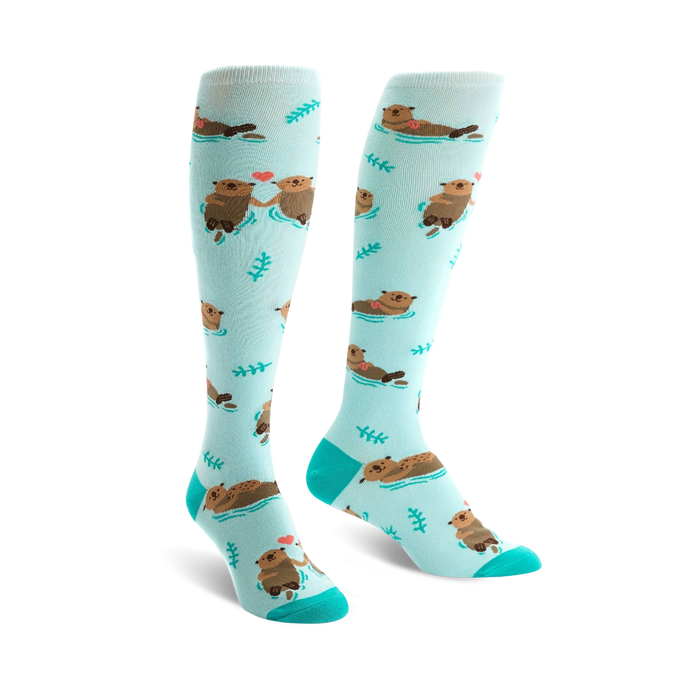 light blue knee high women's socks with cartoon otters holding hands and green plants.   }}