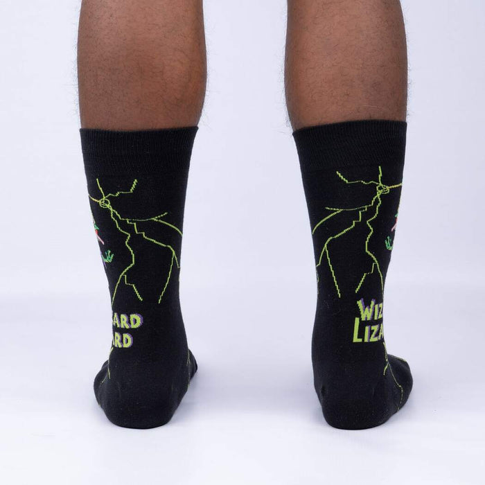 A pair of black socks with a green and yellow design of a wizard and a lizard on each sock. The text 