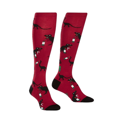 Pair of red knee-high socks with black dinosaurs drinking wine bottles. Fun and quirky design.