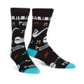 Pair of black crew socks with a jazz-themed design. Features musical instruments, notes, and piano keys, accented with teal at the cuff.