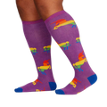 Lifestyle shot showing the socks on a person's legs; purple socks with rainbow unicorns visible.