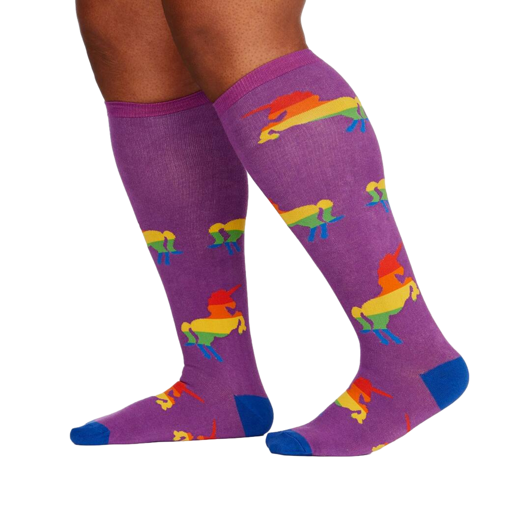 Lifestyle shot showing the socks on a person's legs; purple socks with rainbow unicorns visible.