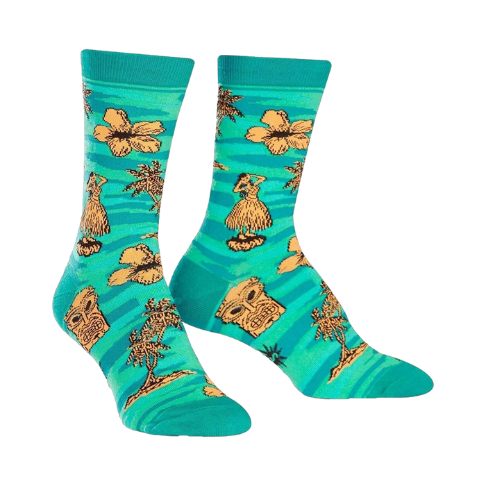 Crew socks in teal, adorned with orange hibiscus flowers, hula dancers, tiki masks, and palm trees. A fun, tropical design. }}