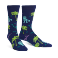 Pair of navy blue crew socks featuring a fun pattern of green and purple dinosaurs and palm trees.