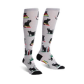 Pair of knee-high socks on a white background.  They're light grey with a pattern of black cats sitting on stacks of colorful books.