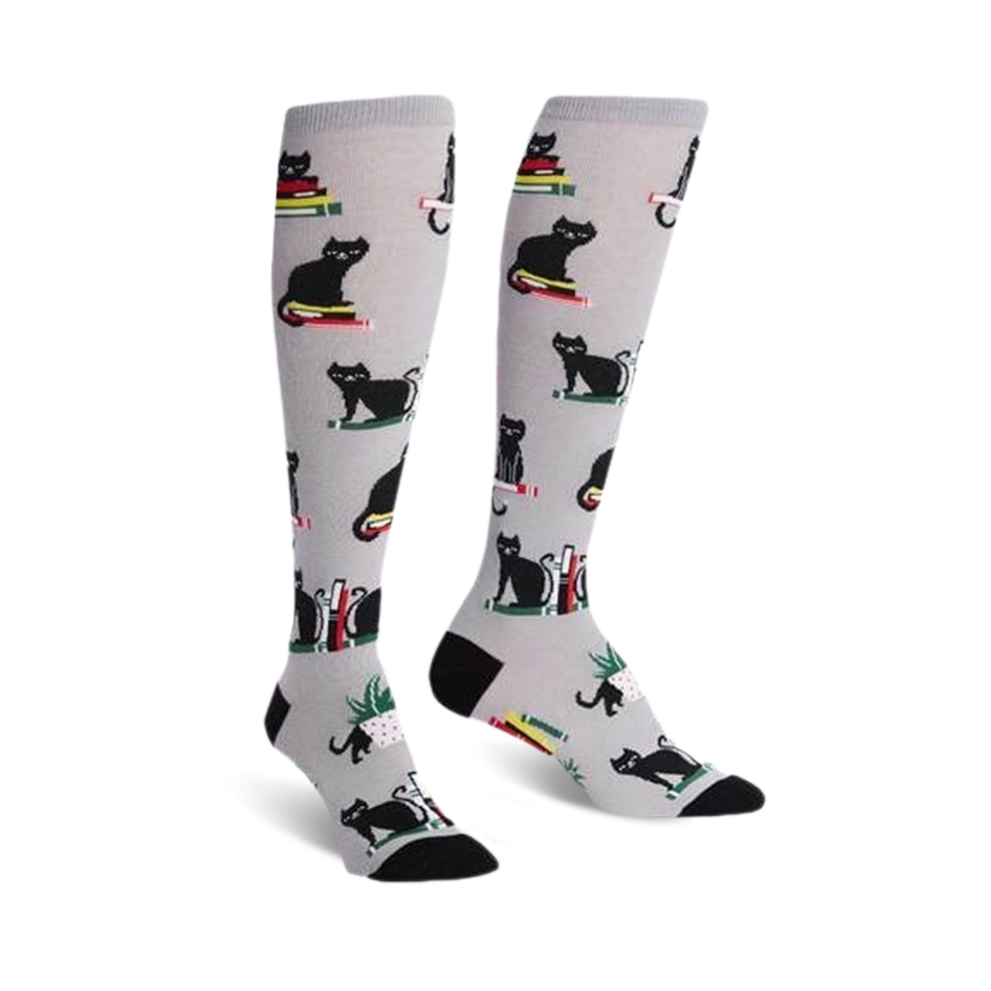 Pair of knee-high socks on a white background.  They're light grey with a pattern of black cats sitting on stacks of colorful books.