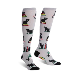 gray knee-high women's socks with a pattern of black cats sitting on books.  