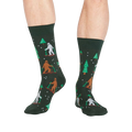 Lifestyle shot showing the 'Ready, Yeti, Go!' socks on a person's legs.  The socks are dark green with a festive pattern.