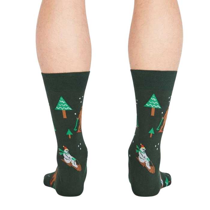 A pair of green socks with a pattern of Bigfoot and a bear skiing down a mountain on them.