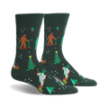 A pair of dark green crew socks with a whimsical Christmas design. Features Bigfoot characters skiing, snowmen, and Christmas trees.