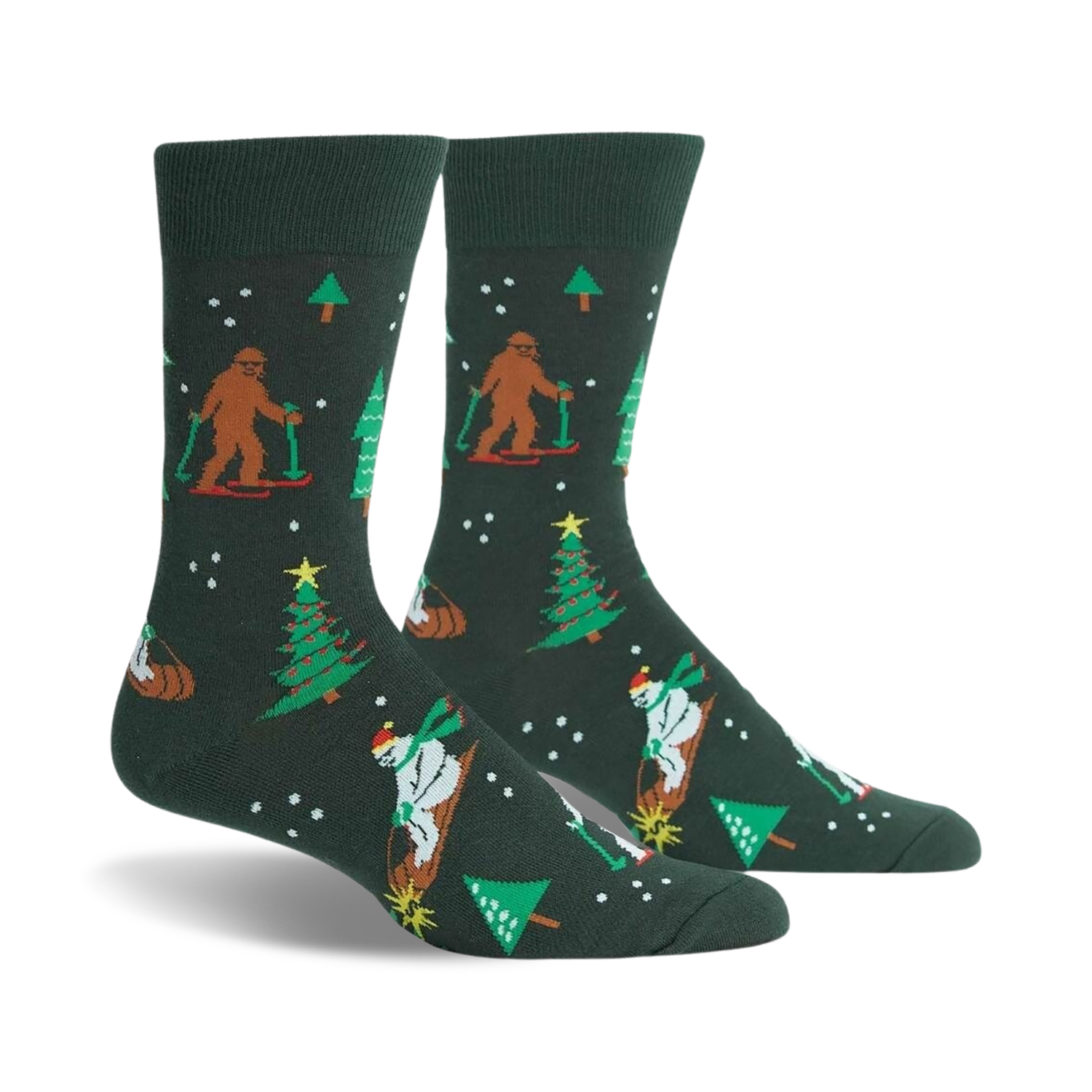 A pair of dark green crew socks with a whimsical Christmas design. Features Bigfoot characters skiing, snowmen, and Christmas trees.