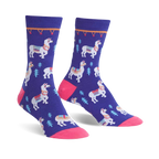 Pair of purple crew socks featuring white llamas with colorful saddles and small green trees. Pink toe and cuff detail.