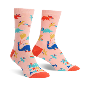 Crew socks in pink featuring colorful dinosaurs, balloons, and party hats. Fun, playful design.