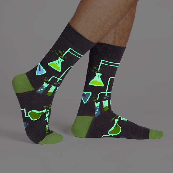 A pair of gray socks with a pattern of blue and green beakers and test tubes.