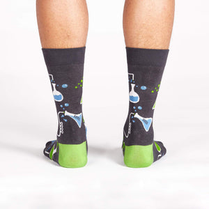 A pair of gray socks with a pattern of blue and green beakers and test tubes.