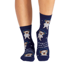 Lifestyle shot showing the socks on a person's legs. The socks are navy blue with pugs dressed as astronauts.