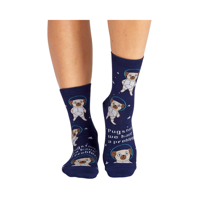 Lifestyle shot showing the socks on a person's legs. The socks are navy blue with pugs dressed as astronauts.