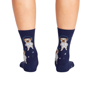 A pair of blue socks with a repeating pattern of cartoon pugs in space suits against a background of stars.