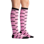 Lifestyle shot showing the Mustache knee-high socks on a person's legs. Pink and black pattern.
