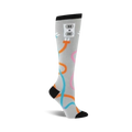 Knee-high socks in grey with an illustrated electrical outlet and colorful cord designs. Orange, teal, and pink accents on a light grey background.