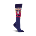 Knee-high socks in navy blue featuring a colorful Nutcracker design. The Nutcracker is depicted from the waist up, wearing a red coat and black hat.