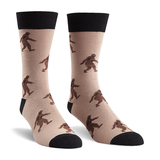 Sasquatch crew socks with brown Bigfoot figures on tan, featuring black cuffs, heels, and toes.