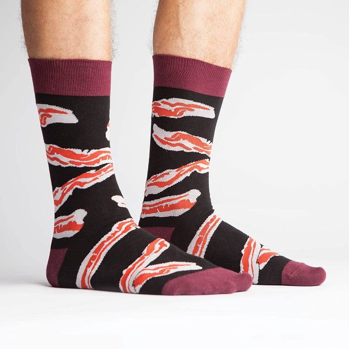 A pair of black socks with a pattern of bacon strips. The socks have a maroon toe, heel, and cuff.