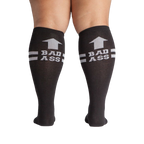 Flat lay product shot: Two black 'Bad Ass' knee-high socks laid flat.