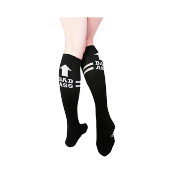 black and white knee-high socks featuring bold text "bad ass" and an arrow pointing up.  
