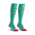 Pair of teal knee-high socks with a repeating pattern of cartoon dinosaurs made of tacos.  Accents of red on the toes and cuffs.