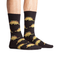 Lifestyle photo showing Tacosaurus socks on a person's feet. The socks are black with a fun taco-dinosaur pattern.