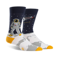 A pair of crew socks; navy blue background with white moon surface, astronaut, rocket, and gold accents.