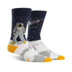 A pair of crew socks; navy blue background with white moon surface, astronaut, rocket, and gold accents.