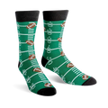 A pair of green crew socks with a football field design, including yard lines and brown footballs. 