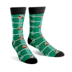 A pair of green crew socks with a football field design, including yard lines and brown footballs. 