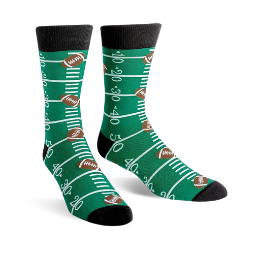 A pair of green crew socks with a football field design, including yard lines and brown footballs. 