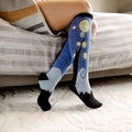[lf] Person relaxing on a bed, wearing blue "Starry Night" patterned socks with black toes and heels.