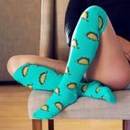 [lf] Person seated, wearing teal knee-high socks with cute taco dinosaur patterns.