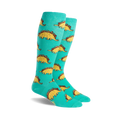 Pair of teal knee-high socks with a repeating pattern of cartoon dinosaurs shaped like tacos. 