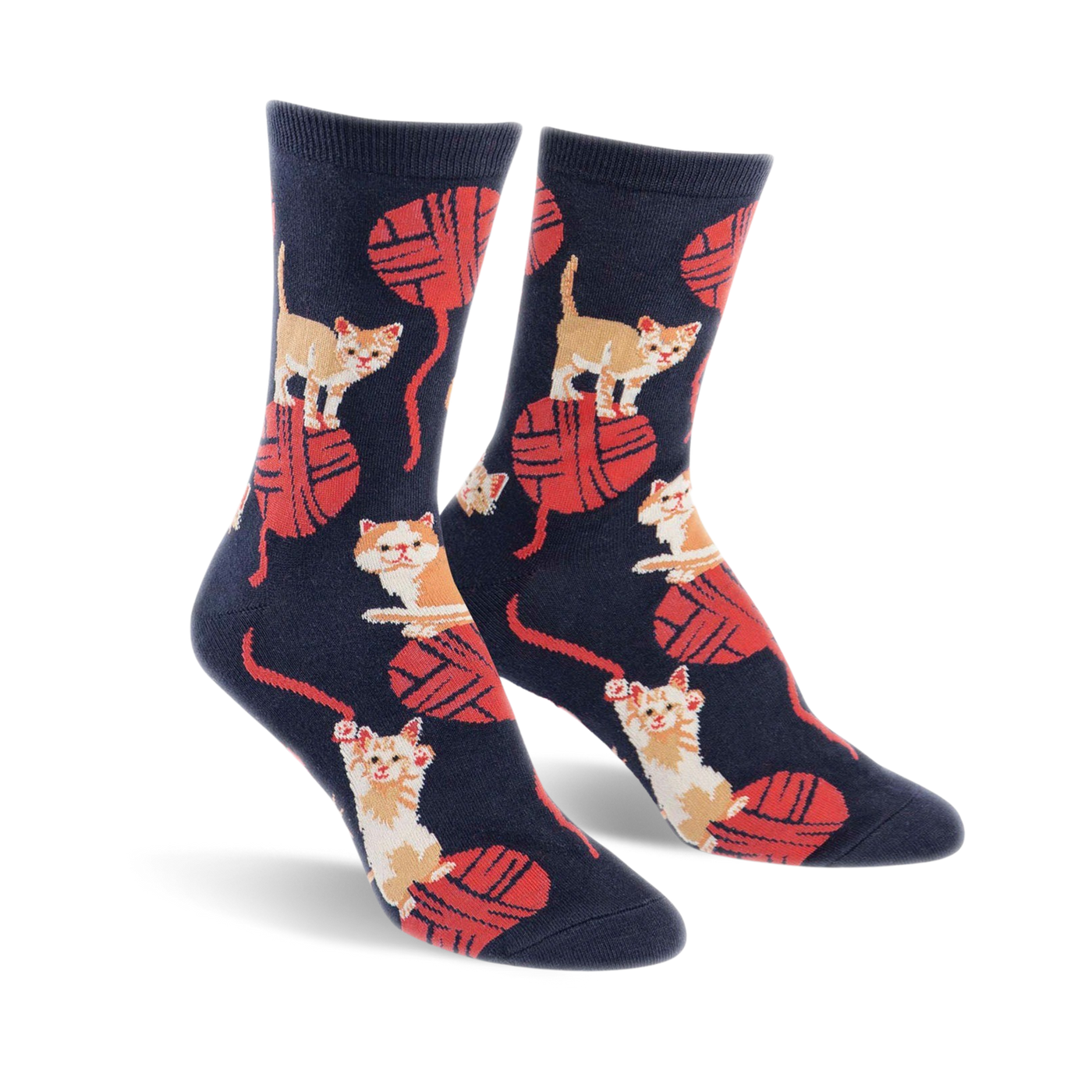 A pair of crew socks in navy blue with a playful pattern of orange kittens batting at red yarn balls.
