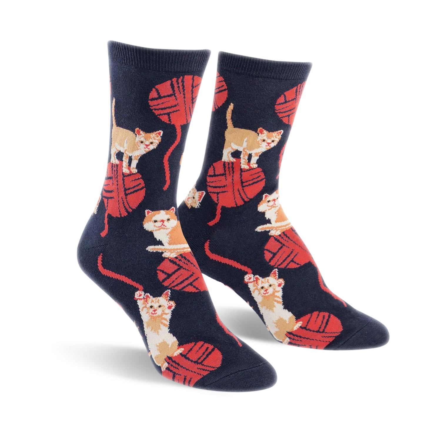 A pair of crew socks in navy blue with a playful pattern of orange kittens batting at red yarn balls.