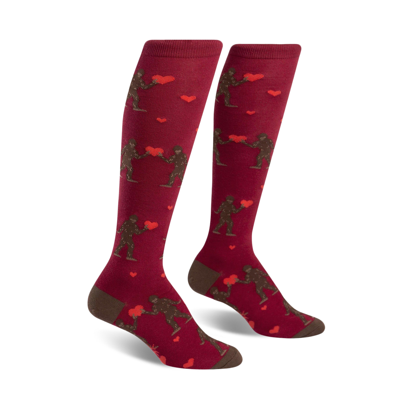 Pair of maroon knee-high socks. Features brown Bigfoot figures exchanging red hearts. Cute and quirky Valentine's Day design.