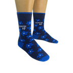Pair of navy blue crew socks with bright blue flowers and 'DOMESTIC AF' text, shown on a model's feet.