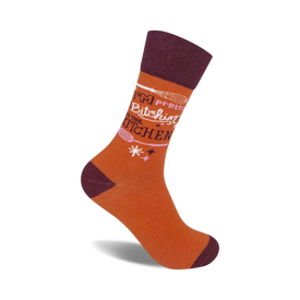 crew socks in orange with the words "i'm pretty bitchin' in the kitchen". light pink whisk illustration and 3 pink asterisks.   
