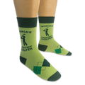 Person wearing a pair of light green World's Okayest Golfer socks on a black background, showing the side text and argyle.