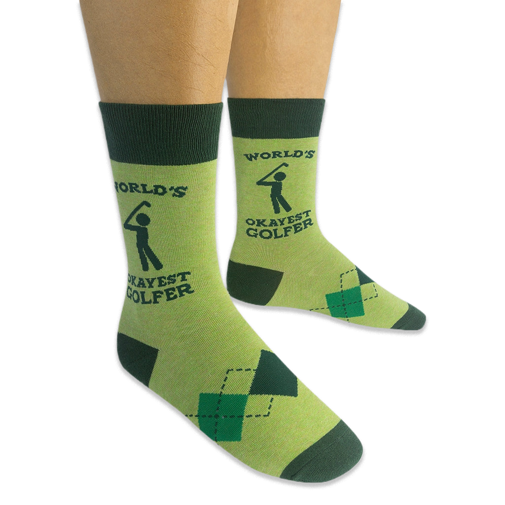 Person wearing a pair of light green World's Okayest Golfer socks on a black background, showing the side text and argyle.