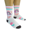 Person wearing cream socks with a pink-haired cowgirl, Let's go Girls text, retro stripes, and a pink rose on a black backdrop.